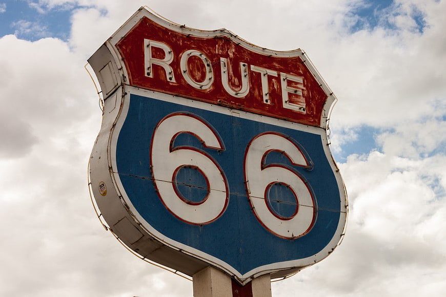 Vintage Route 66 Road Sign Against Cloudy Sky