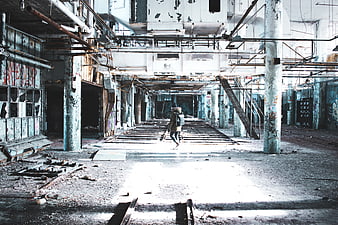 Woman walking through abandoned industrial factory interior