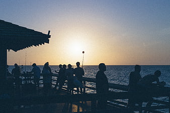 Silhouettes of People Fishing on a Pier at Sunset