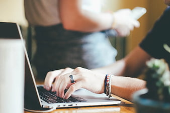 Close-up of hands typing on laptop keyboard with ring