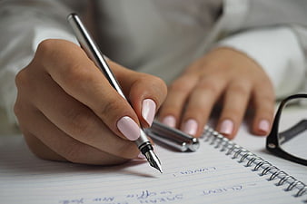 Close-up of Woman Writing in Notebook with Pen