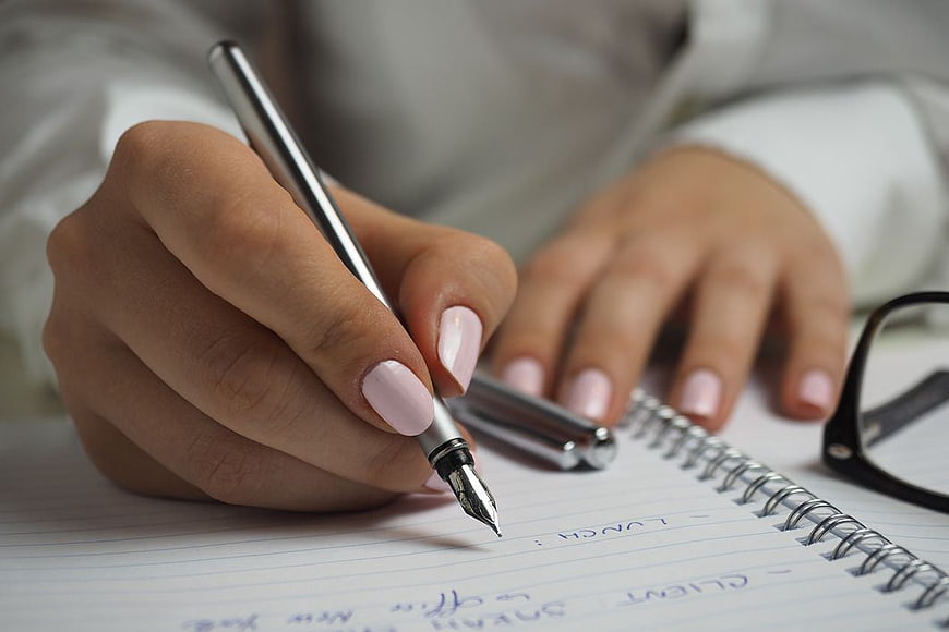 Close-up of Woman Writing in Notebook with Pen