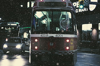 Red streetcar in snowy city night traffic