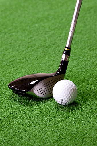 Golf club and ball on green grass