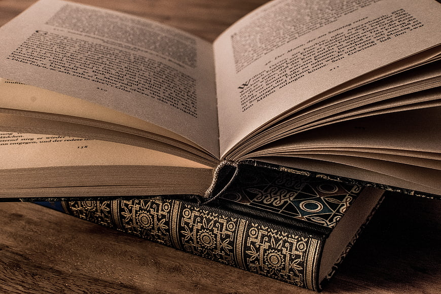 Close-up of open vintage book with ornate spine on wood