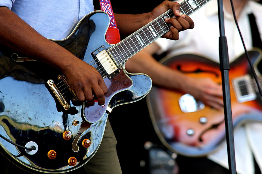 Close-up of musician playing black electric guitar on stage
