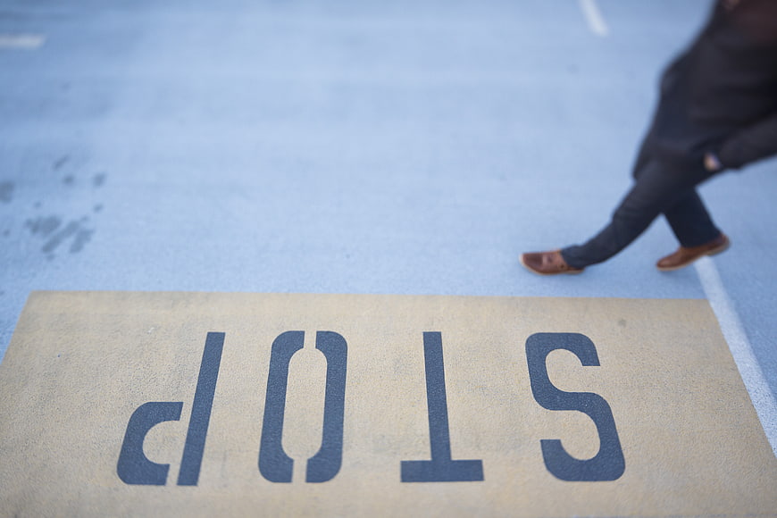 Upside down stop sign on pavement with walking pedestrian
