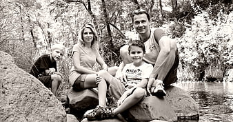 Family of Four Sitting on Rocks by a River in Black and White