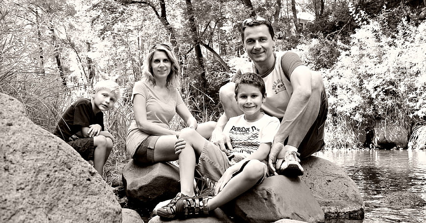 Family of Four Sitting on Rocks by a River in Black and White