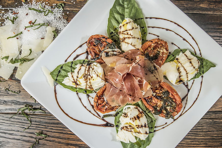 Overhead view of gourmet caprese salad with prosciutto and balsamic glaze