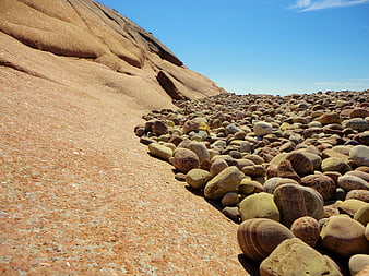 Smooth pebbles on a rocky slope under a blue sky