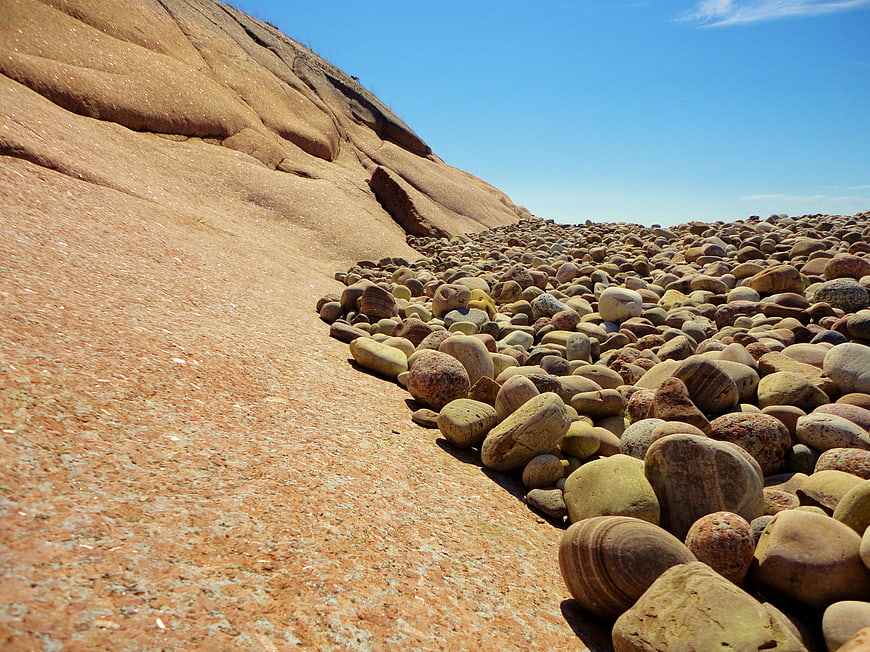 Smooth pebbles on a rocky slope under a blue sky