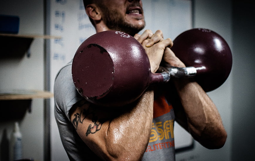 Man lifting heavy kettlebell during intense gym workout