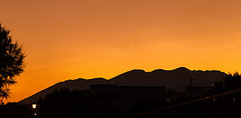 Silhouette of Mountains Against Vibrant Orange Sunset Sky
