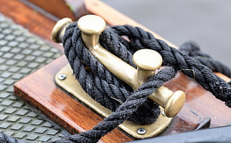 Close-up of black rope on brass cleat