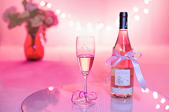 Pink Rosé Wine Bottle and Glass with Ribbon on Pink Background