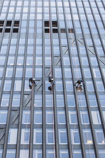 Window cleaners rappelling down modern glass skyscraper facade