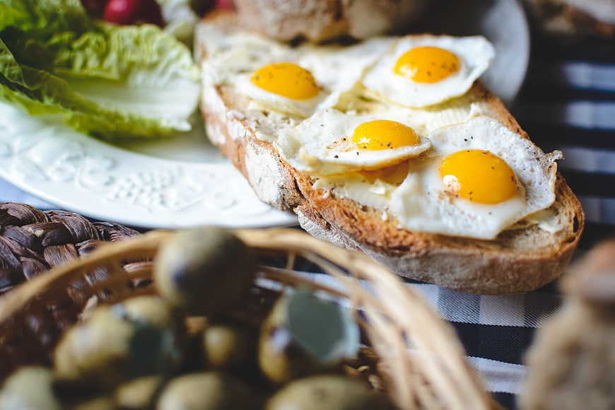 Fried quail eggs on rustic bread with olives and lettuce