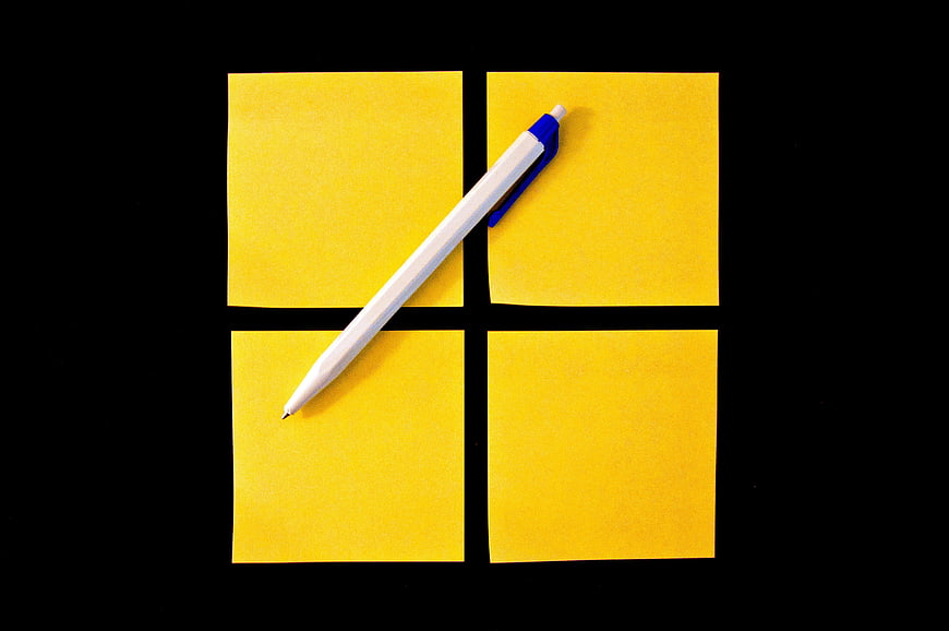 Four yellow sticky notes and a white pen on a black background