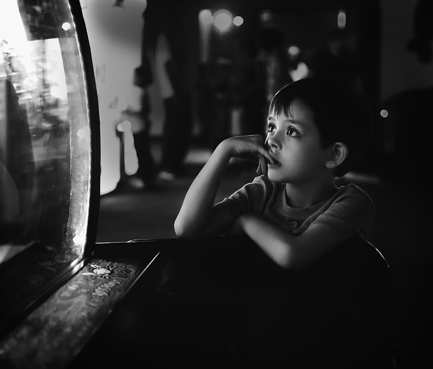 Pensive young boy looking out window in black and white