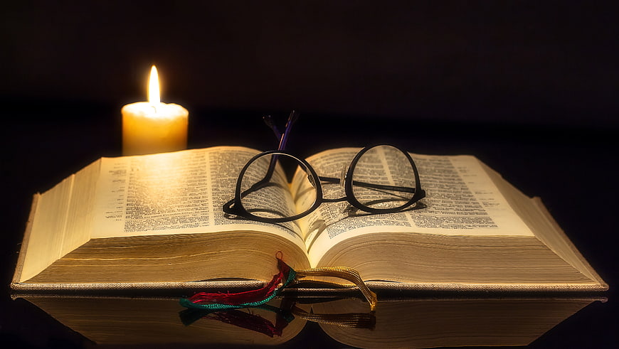Open Bible with Glasses and Candlelight