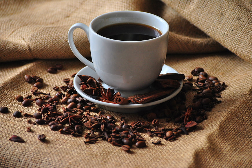 White Cup of Black Coffee with Spices on Burlap