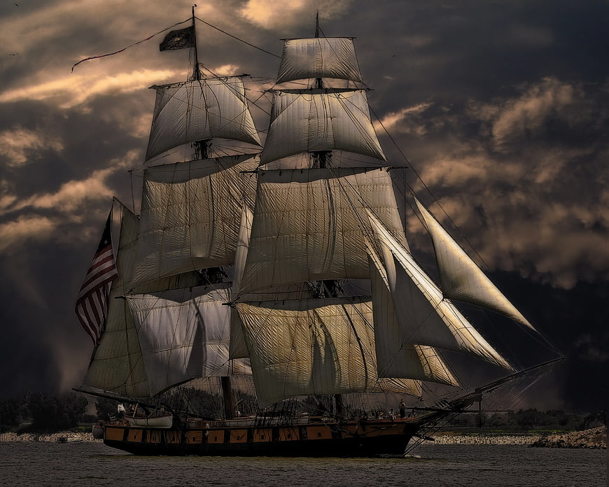 Historic Tall Ship Sailing Under Dramatic Stormy Sky