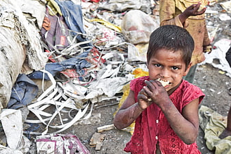 Portrait of a young girl eating amidst a pile of waste