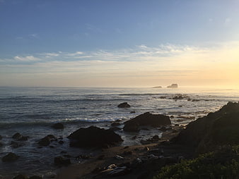 Serene Sunset Over Rocky Coastline with Distant Sea Stacks