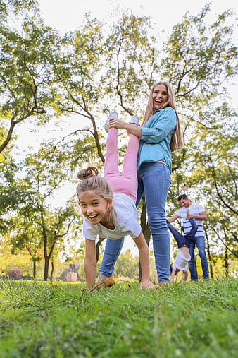 Happy family playing handstands in sunny park