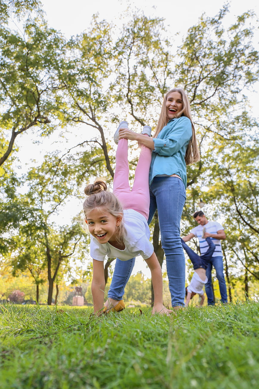 Happy family playing handstands in sunny park