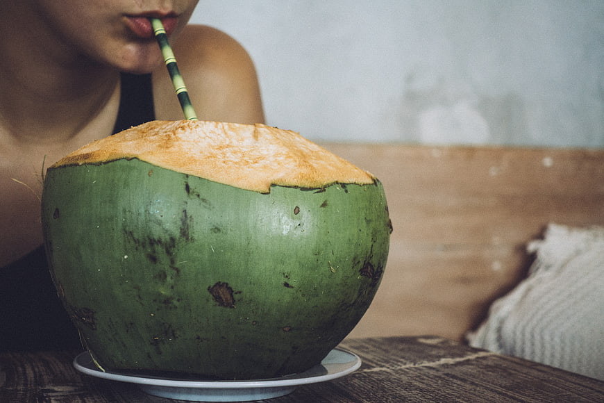 Close-up of woman drinking fresh coconut water with straw