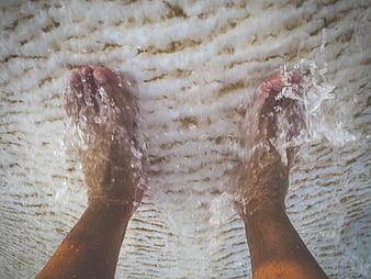 POV bare feet splashing in shallow ocean waves