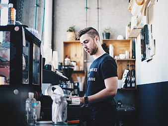 Young male barista working at coffee shop counter