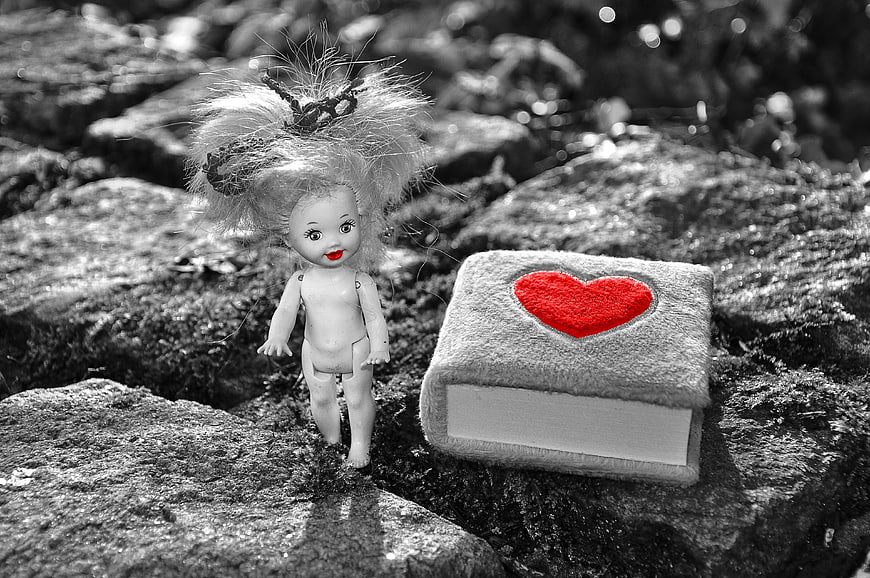 Vintage doll with red heart diary on cobblestones