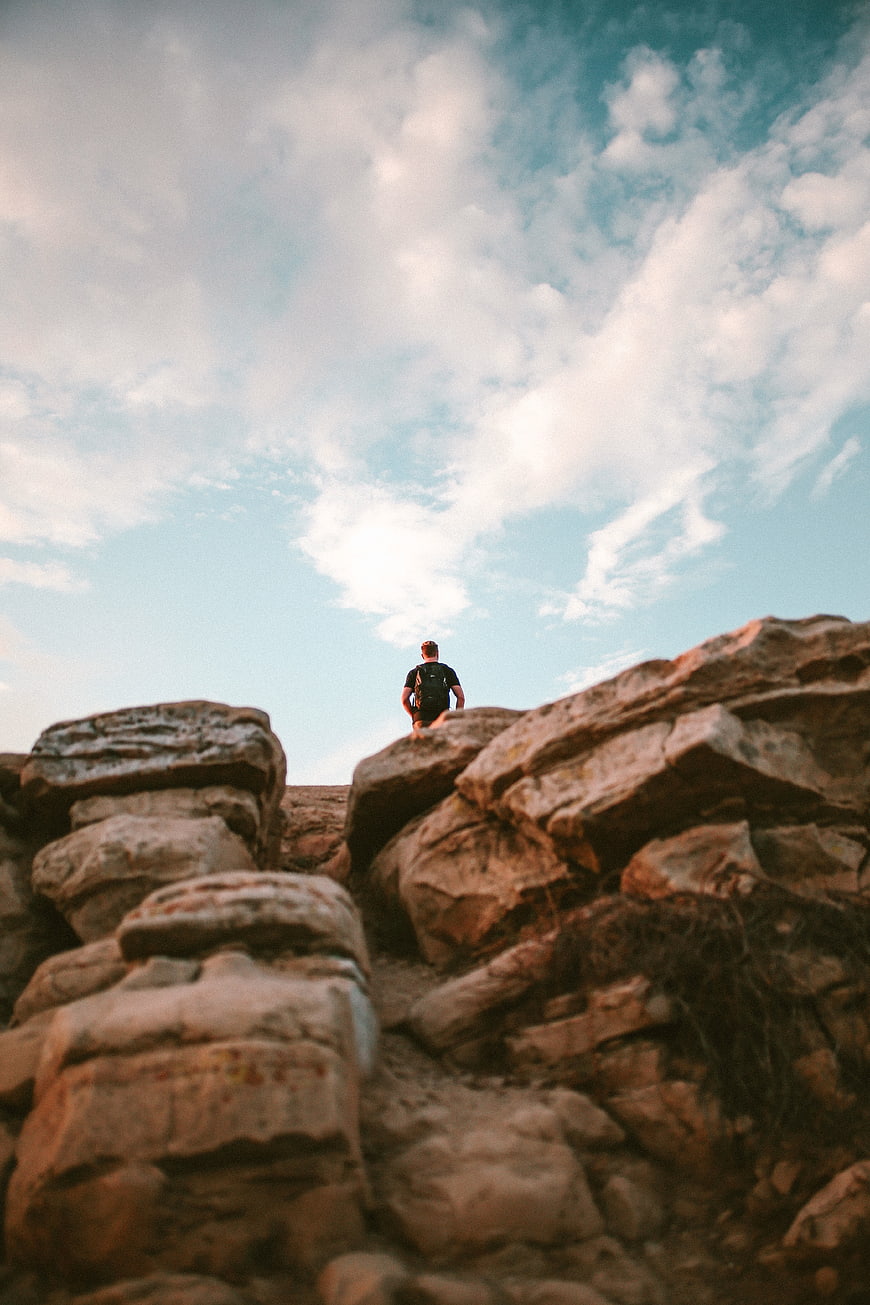 Man hiking on rocky terrain under blue sky