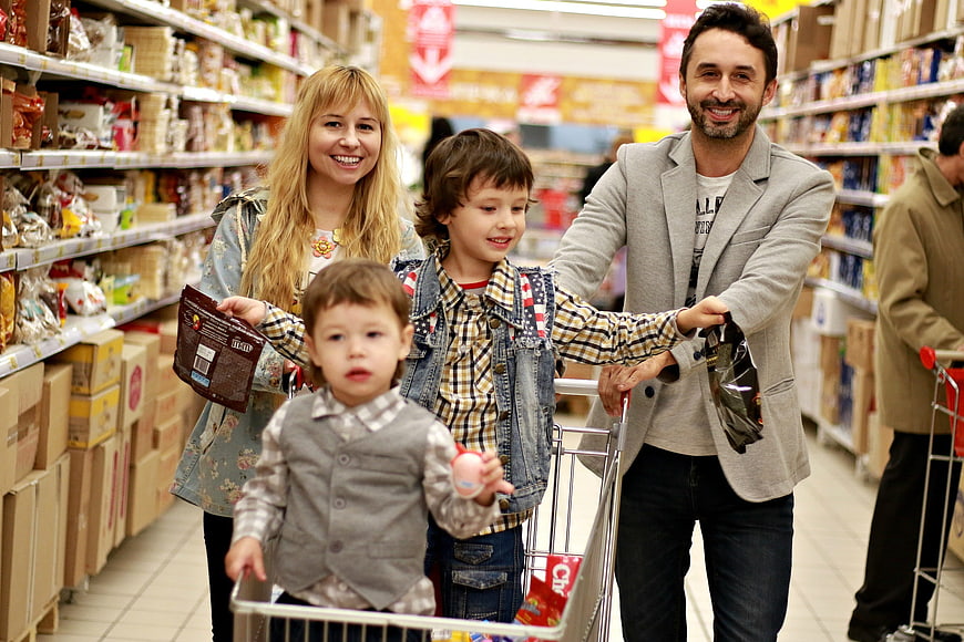 Happy family shopping for groceries with children in cart