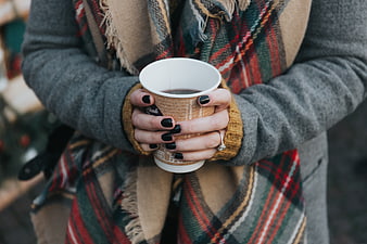 Woman holding hot coffee cup in winter scarf
