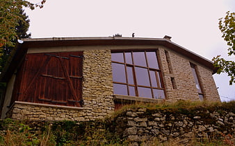 Rustic stone house with large windows and wooden doors