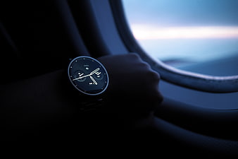 Smartwatch on wrist inside airplane window at dusk