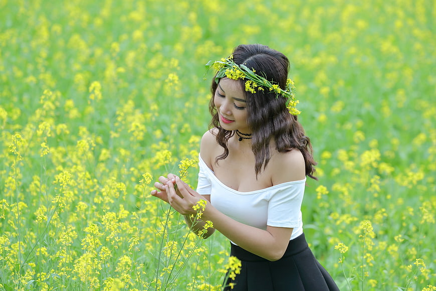 Young woman with flower crown in a field of yellow flowers