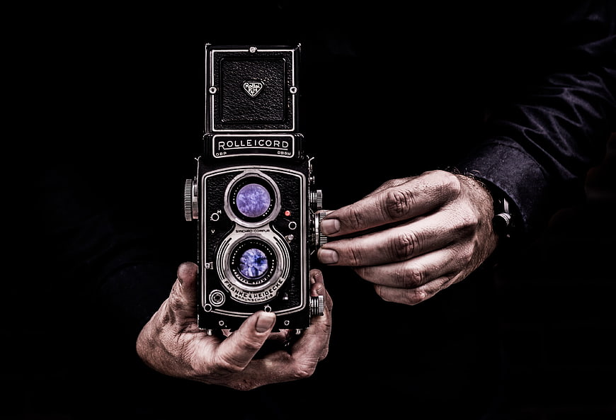 Vintage Rolleicord Camera Held by Hands on Black Background