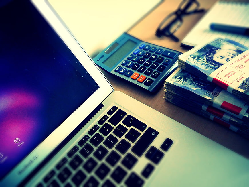 Laptop, Calculator, and Cash on Desk for Finance Concept