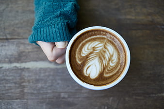 Top View of Hand Holding Latte with Leaf Art