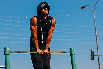 Muscular man performing street workout on pull-up bar