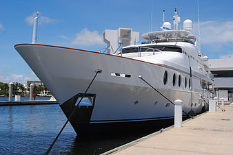 White luxury superyacht docked at marina on sunny day