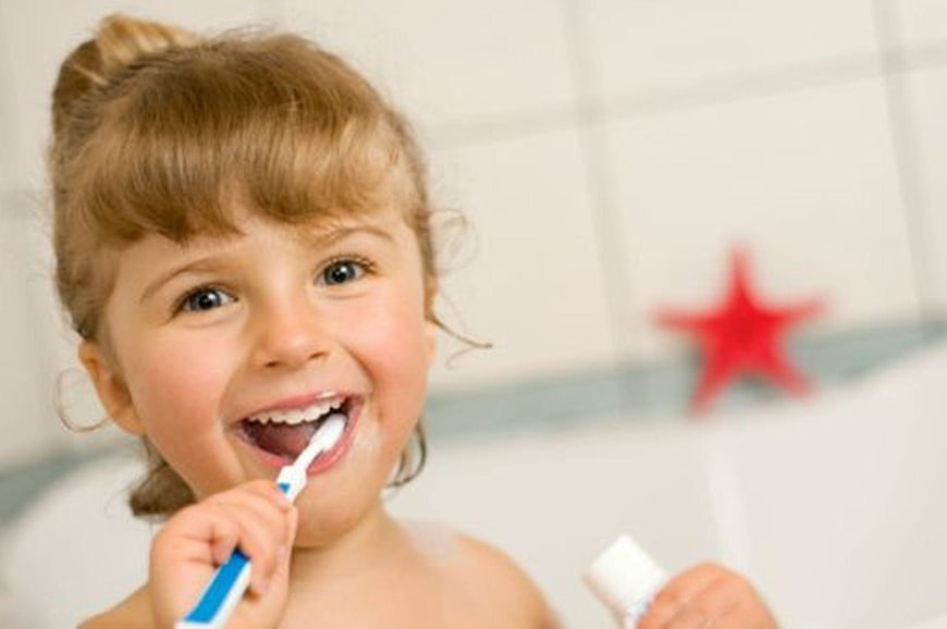 Happy little girl brushing teeth in bathroom