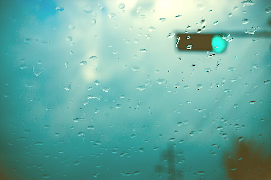Raindrops on Window Glass with Blurred Traffic Light