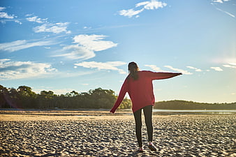 Woman in Red Sweater Walking on Sandy Beach at Sunset