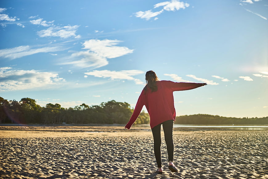 Woman in Red Sweater Walking on Sandy Beach at Sunset